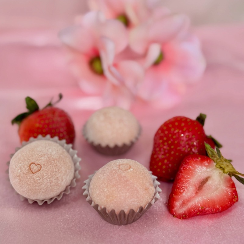 Pink strawberry brigadeiros beside fresh strawberries