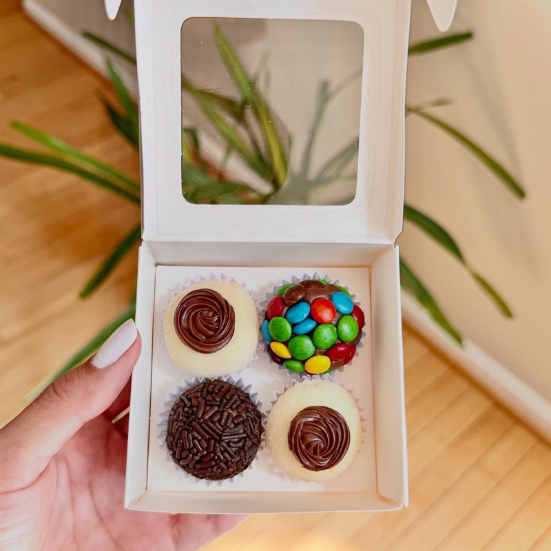 Open box of four assorted brigadeiros held in hand